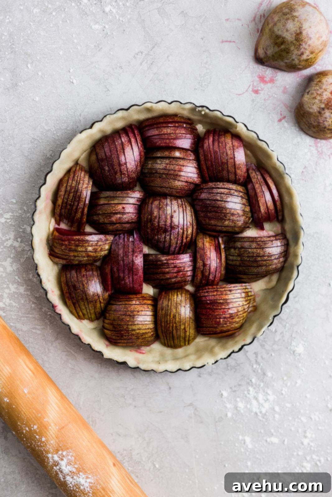 Effortlessly Elegant Plum Tart 3 Thinly sliced ripe plums arranged in concentric circles within an unbaked pie crust, highlighting the elegant preparation.