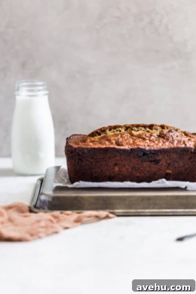 Nut-Free Banana Bread 3 Side view of a freshly baked no nut banana bread loaf sitting on an upside down sheet tray, ready for glazing.