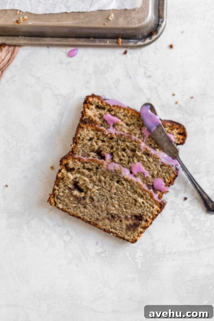 Nut-Free Banana Bread 4 Three perfectly sliced pieces of no nut banana bread, with a small butter knife resting on top, showcasing its moist texture.