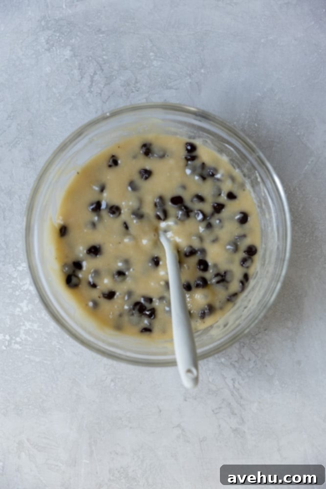 Irresistible Gooey One Bowl Blondie Cookies 4 Blondie batter with numerous semi-sweet chocolate chips folded in, ready for baking, in a glass mixing bowl.