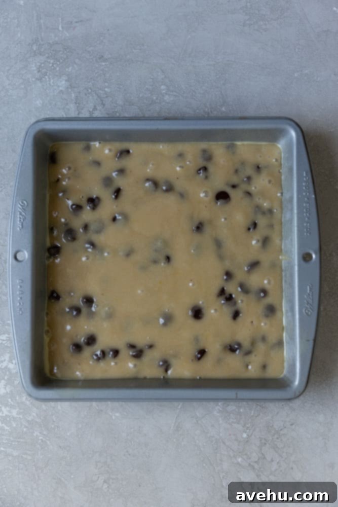 Irresistible Gooey One Bowl Blondie Cookies 5 Raw blondie batter spread evenly in a square metal baking pan, ready to be placed in the oven.