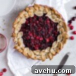 A decorative leaf pattern on a cranberry pie sitting on a white napkin on a gray background.