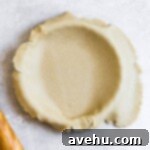 freshly rolled pie dough in its pan with some overhang on the right side.