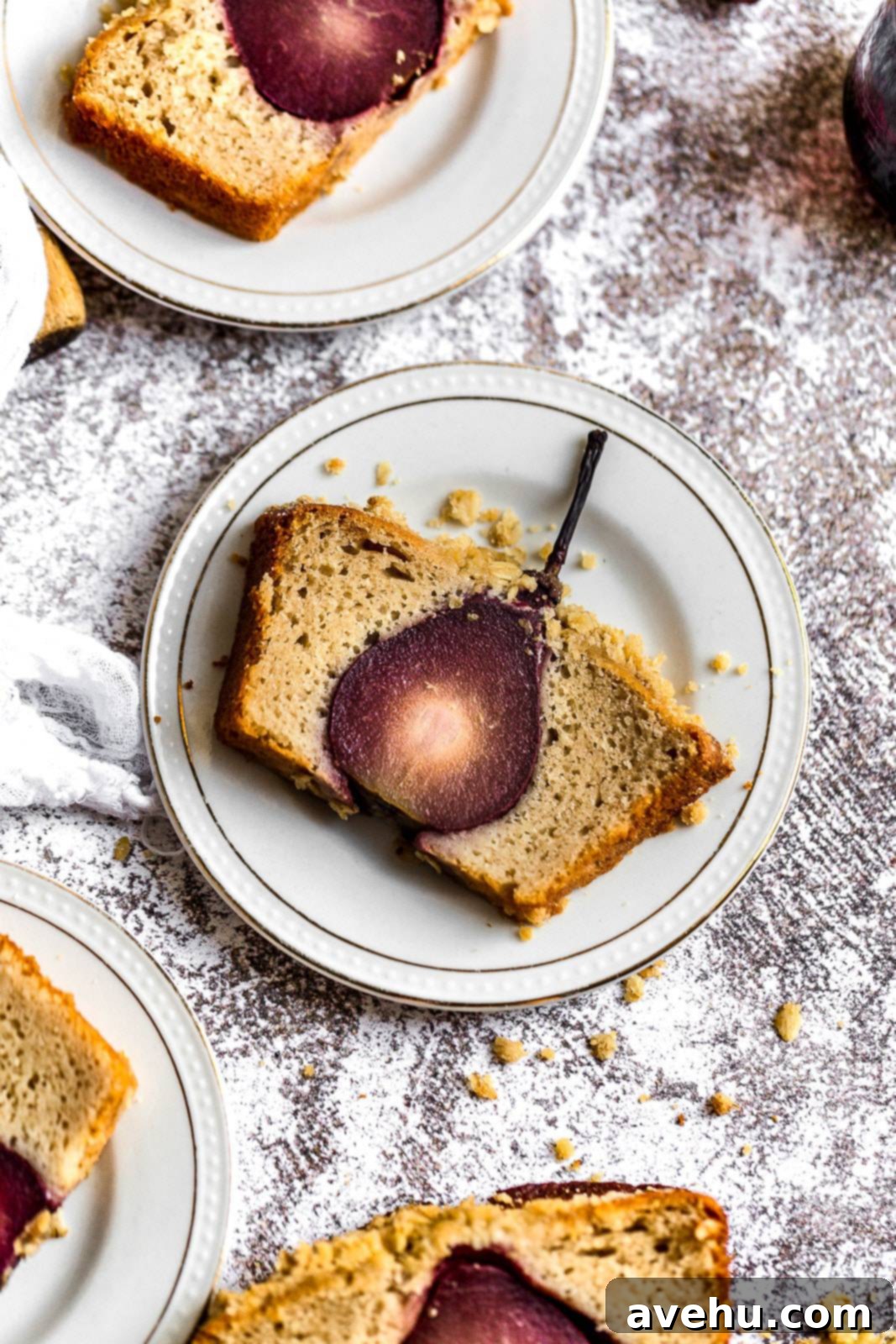 Sweet Pear Streusel Delight 2 A slice of a cake that has a pear baked inside on a white plate, showcasing the vibrant red wine poached pear in the center.