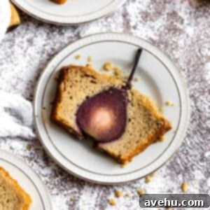 Sweet Pear Streusel Delight 8 A slice of a cake that has a pear baked inside on a white plate, showcasing the vibrant red wine poached pear in the center.