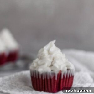 Scarlet Velvet Cheesecake Delights 8 one red velvet cupcake with creamcheese frosting piped on top sitting on white cheesecloth on a gray background