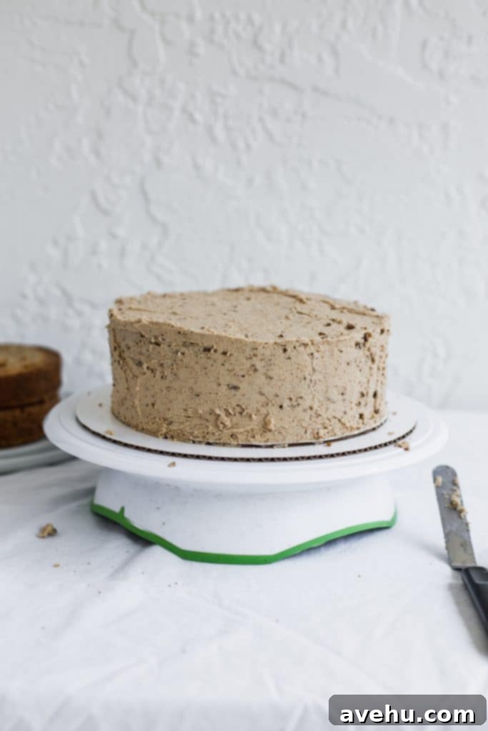 Mastering Two-Tier Cakes: Baking and Stacking Techniques 13 A beige frosting covers a cake sitting on a white cake board and turntable