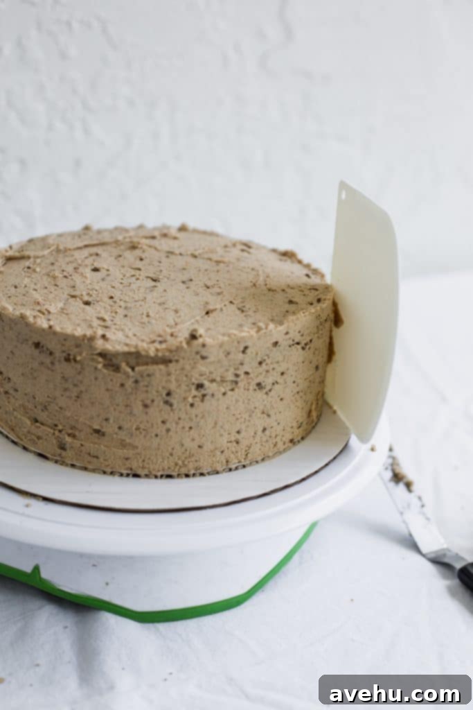 Mastering Two-Tier Cakes: Baking and Stacking Techniques 14 A white bench scraper sticking to the side of a beige frosted cake