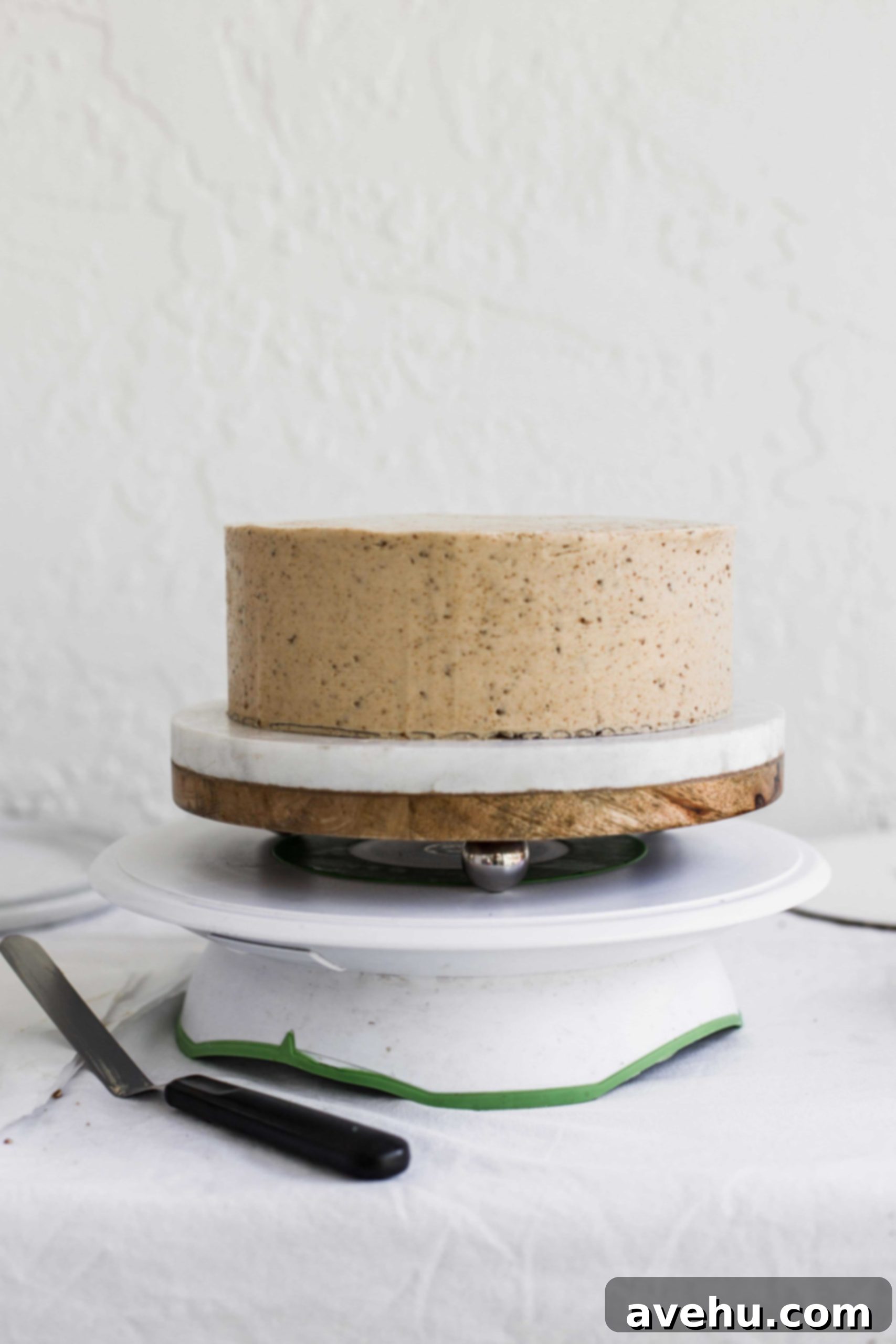 Mastering Two-Tier Cakes: Baking and Stacking Techniques 16 a beige cake sitting on a white and brown cake stand