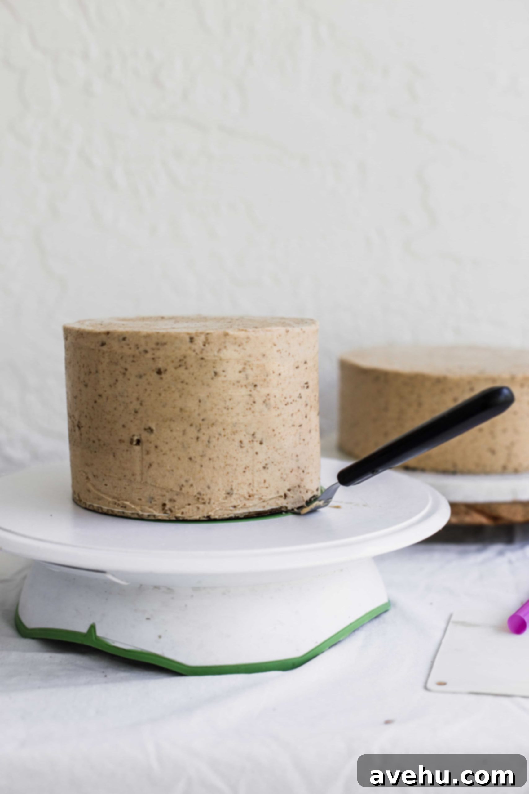 Mastering Two-Tier Cakes: Baking and Stacking Techniques 17 An offset spatula lifting up a cake on a white turntable
