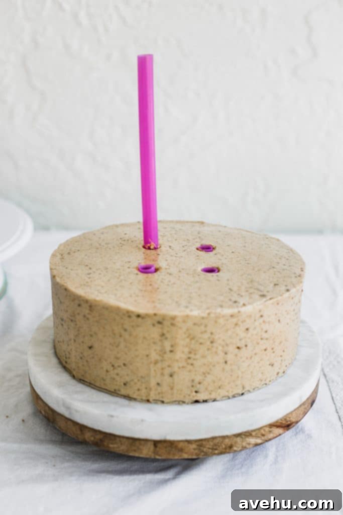 Mastering Two-Tier Cakes: Baking and Stacking Techniques 18 A pink straw being inserted in the middle of a beige cake