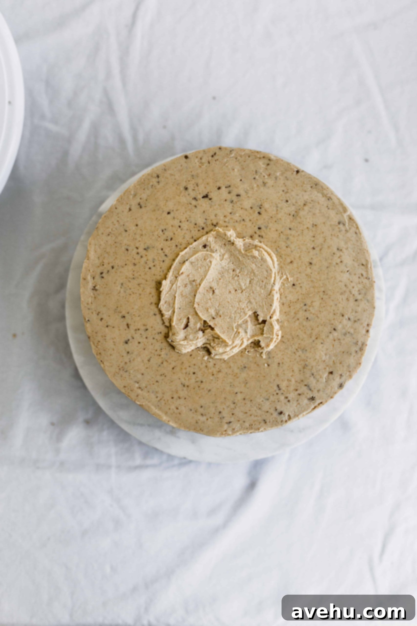 Mastering Two-Tier Cakes: Baking and Stacking Techniques 22 Frosting smoothed onto the top of a beige cake