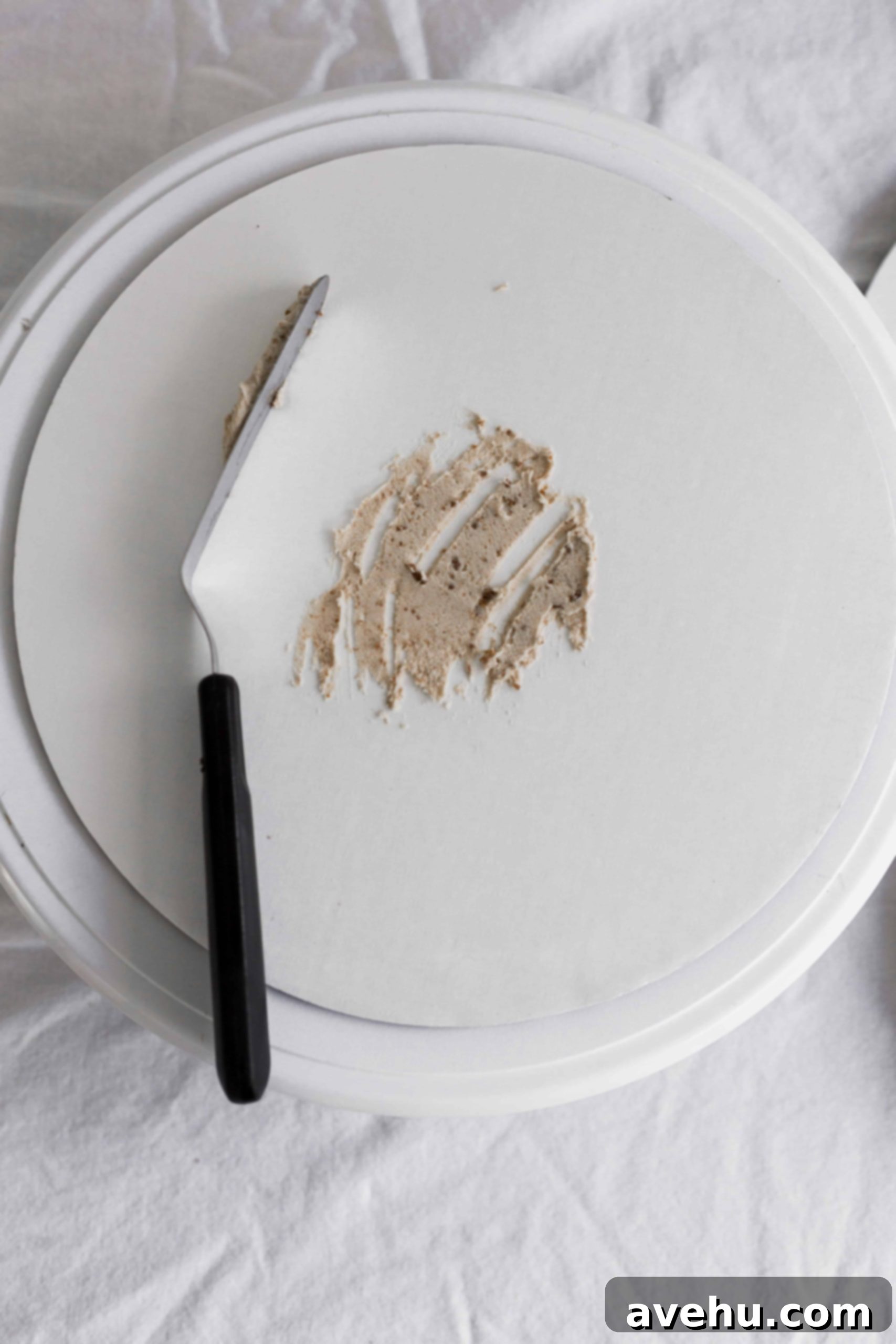 Mastering Two-Tier Cakes: Baking and Stacking Techniques 7 A cake board with frosting dabbed on to the middle and an offset spatula set to the side