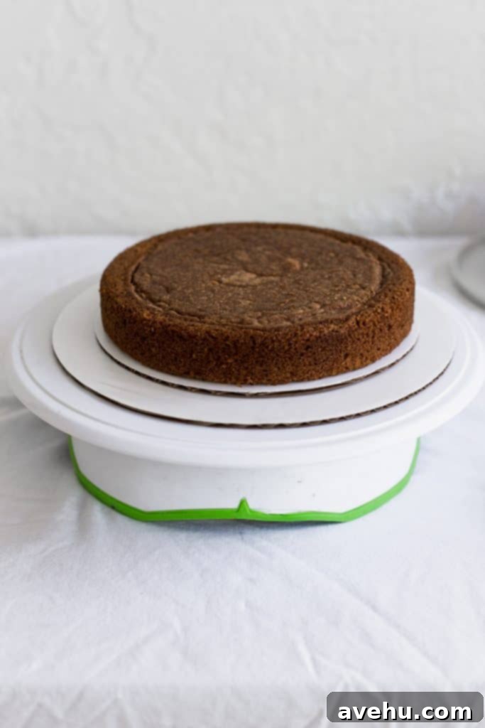 Mastering Two-Tier Cakes: Baking and Stacking Techniques 8 A cake sitting on 2 different size white cake boards on a cake turn table