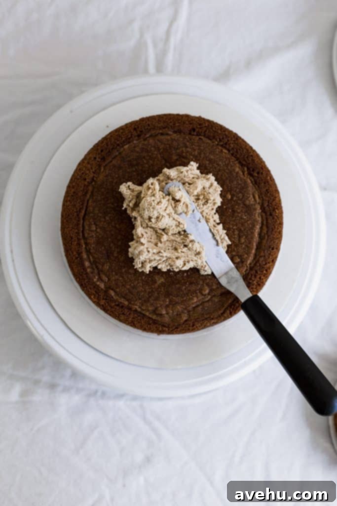 Mastering Two-Tier Cakes: Baking and Stacking Techniques 9 An offset spatula spreading cookie butter buttercream on a cake