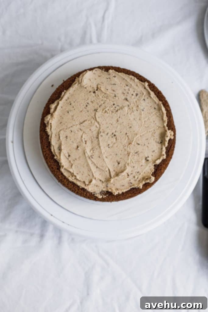 Mastering Two-Tier Cakes: Baking and Stacking Techniques 10 A beige frosting spread over a cake on a white cake turntable