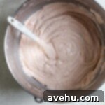 Luscious Strawberry Bundt Cake 7 A vibrant pink cake batter fills a mixing bowl, showcasing the natural color infused by fresh strawberries, ready to be poured into the bundt pan.