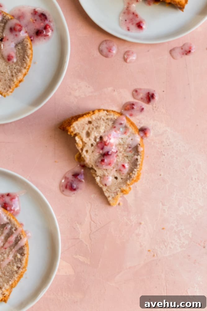 Luscious Strawberry Bundt Cake 4 A perfectly sliced piece of moist bundt cake, elegantly drizzled with a homemade pink strawberry glaze, resting on a charming pink surface, ready to be enjoyed.