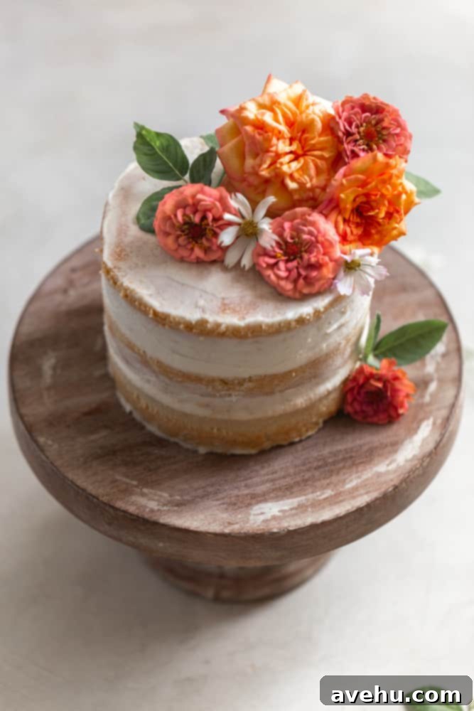 Your Guide to Stunning Floral Naked Cakes 5 A beautifully decorated naked cake topped with an array of fresh flowers, displayed on a wooden cake stand.