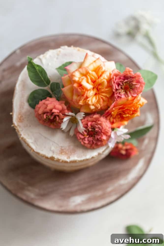 Your Guide to Stunning Floral Naked Cakes 6 A white cake adorned with vibrant flowers and greenery on a rustic wood surface, highlighting detailed floral arrangement.