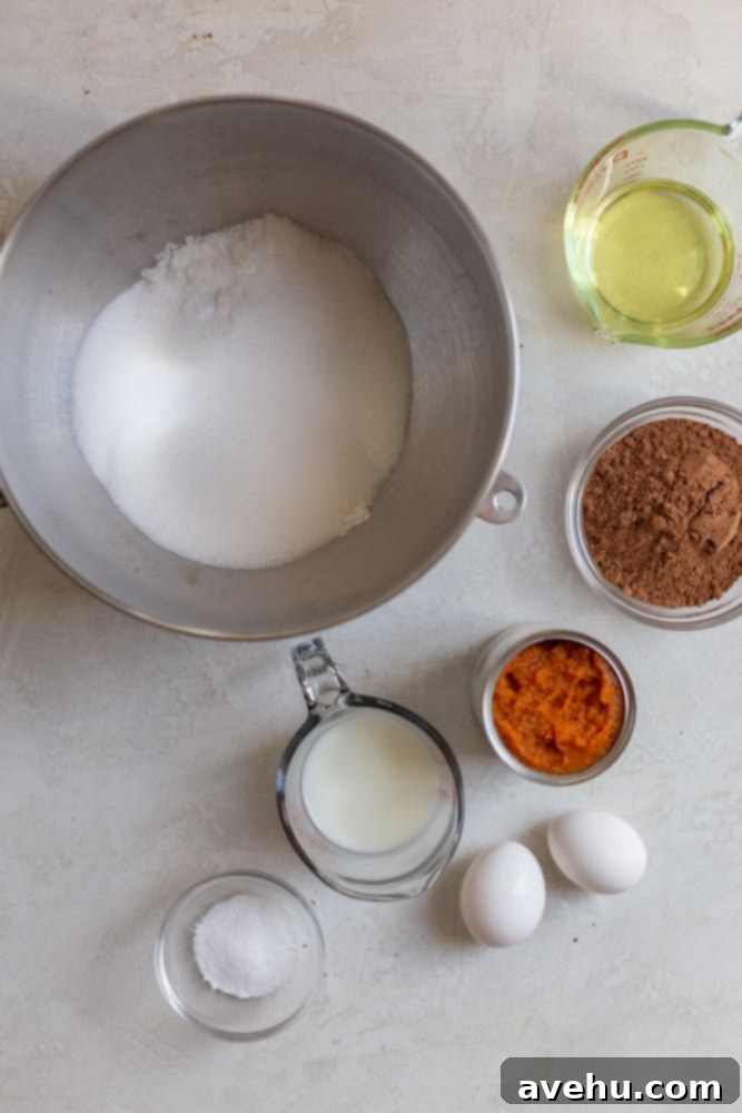Decadent Chocolate Pumpkin Sheet Cake 3 A selection of fresh ingredients laid out for a chocolate pumpkin cake, including flour, sugar, cocoa powder, eggs, oil, buttermilk, and canned pumpkin.