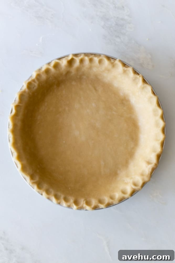 Layers of Perfection: Flaky Pie Crust 2 Unbaked pie crust with crimped edges on a white surface, ready for baking. This visually appealing image showcases the perfect texture and craftsmanship of a homemade flaky pie crust.