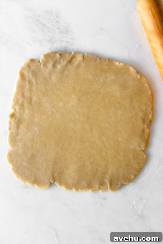 Layers of Perfection: Flaky Pie Crust 11 A perfectly rolled-out pie crust, forming a large, uniform circle on a pristine white surface, ready for transfer to a pie pan.