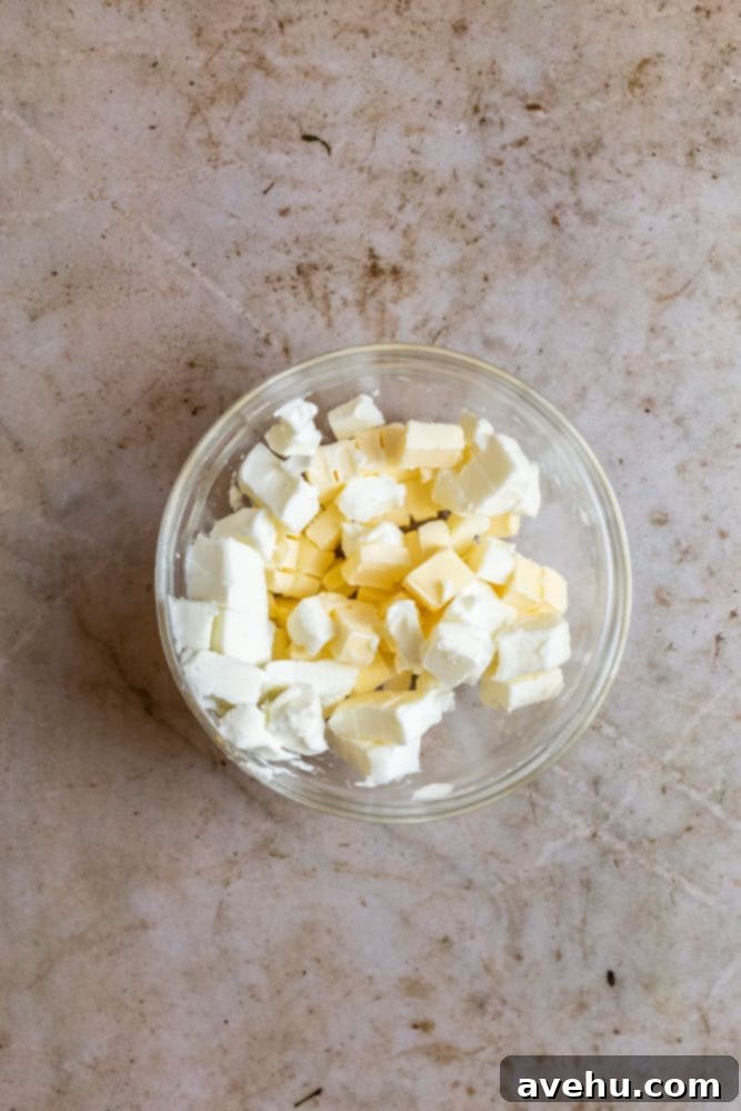 Layers of Perfection: Flaky Pie Crust 4 Cold butter and shortening, precisely cubed into small pieces, sitting in a glass bowl on a rustic stained brown surface, ready to be incorporated into the pie dough.