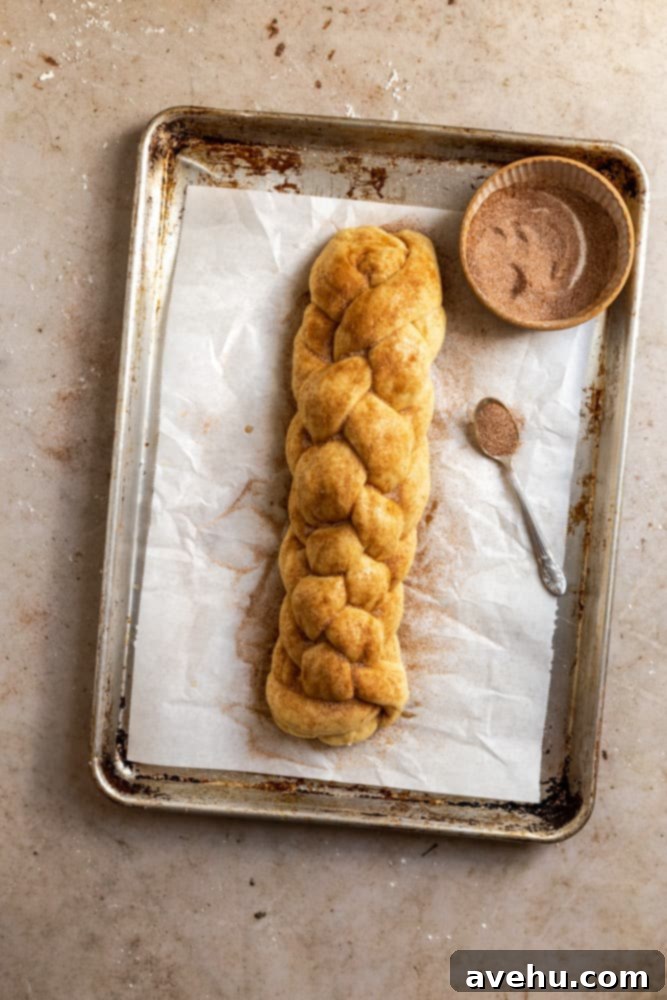 Homemade Challah Perfection 11 A beautiful, unbaked challah braid topped generously with glistening cinnamon sugar, ready for the oven on a baking sheet.