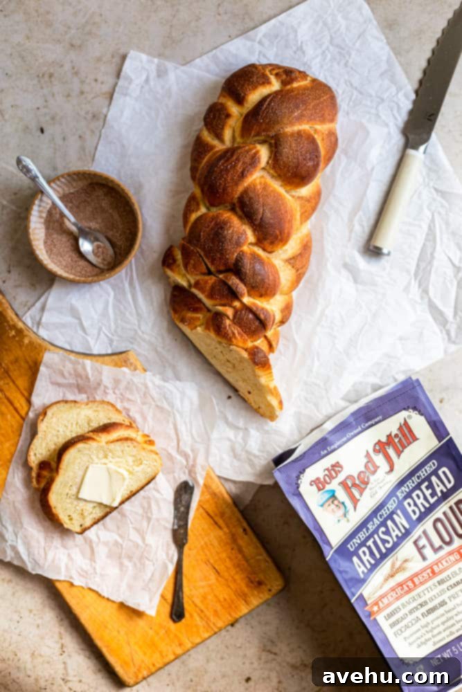 Homemade Challah Perfection 12 A freshly baked, golden-brown challah loaf with cinnamon sugar topping, beautifully sliced on a piece of white parchment paper, ready to be enjoyed.