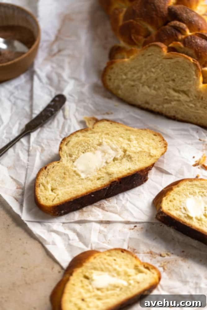 Homemade Challah Perfection 13 A thick slice of golden-brown challah bread with a generous amount of butter melting on top, indicating its soft and warm texture.