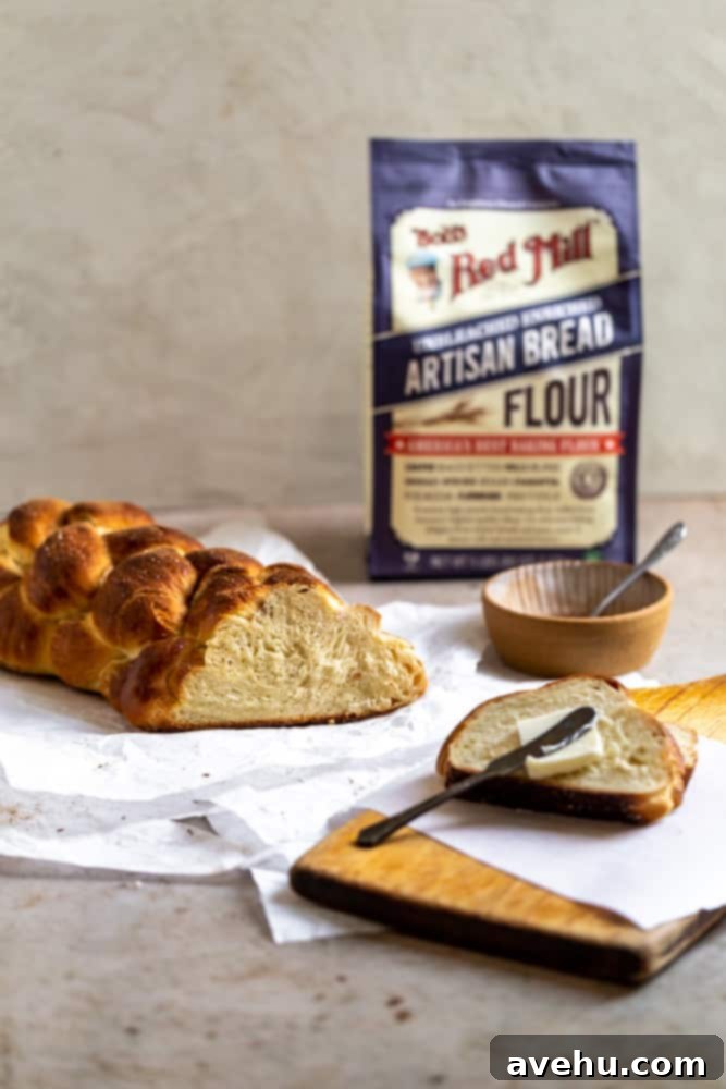 Homemade Challah Perfection 14 A freshly baked challah braid with one end cleanly sliced, showcasing its fluffy interior, resting next to a bag of high-quality bread flour on a gray surface.