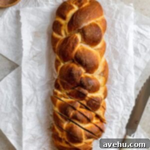 Homemade Challah Perfection 15 A beautiful 6-strand challah braid, freshly baked and sliced, revealing its soft, fluffy interior, resting on a clean white surface. The cinnamon sugar topping is visible.