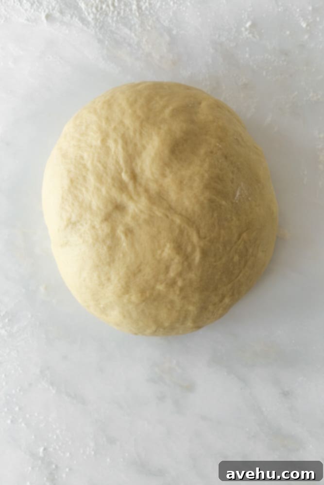 Homemade Challah Perfection 7 A perfectly smooth ball of challah dough on a lightly floured surface, ready for its initial rise.