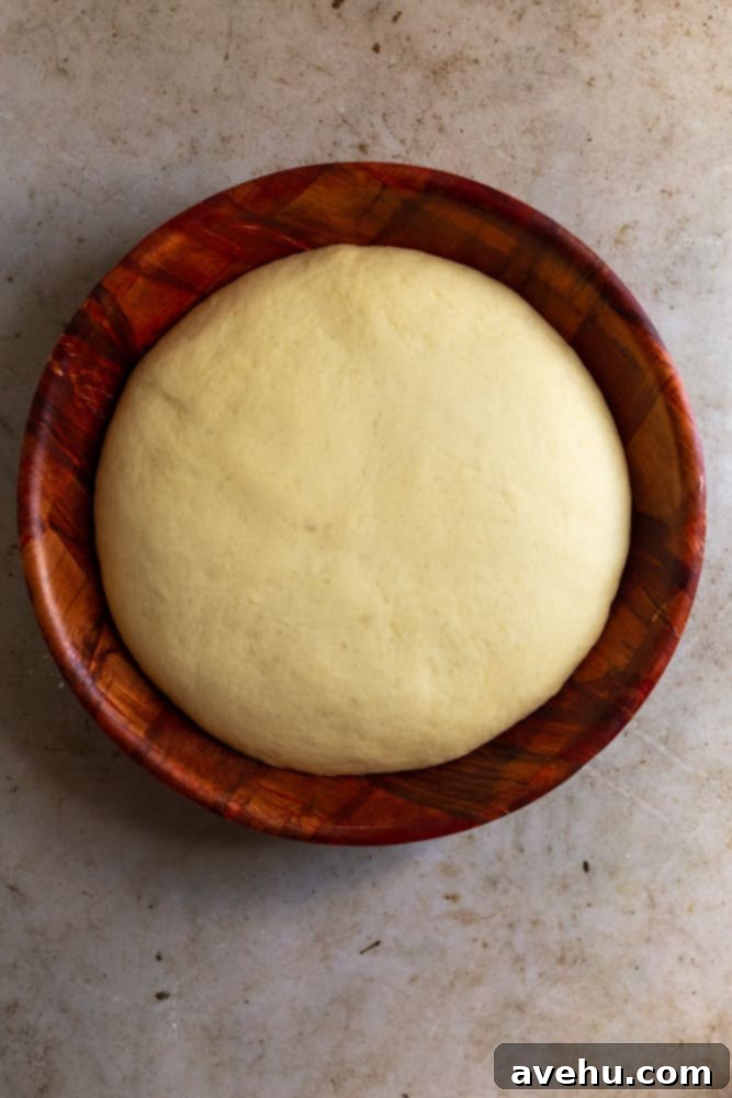 Homemade Challah Perfection 9 Beautifully risen challah dough, significantly doubled in size, filling a wooden bowl after its first bulk fermentation.