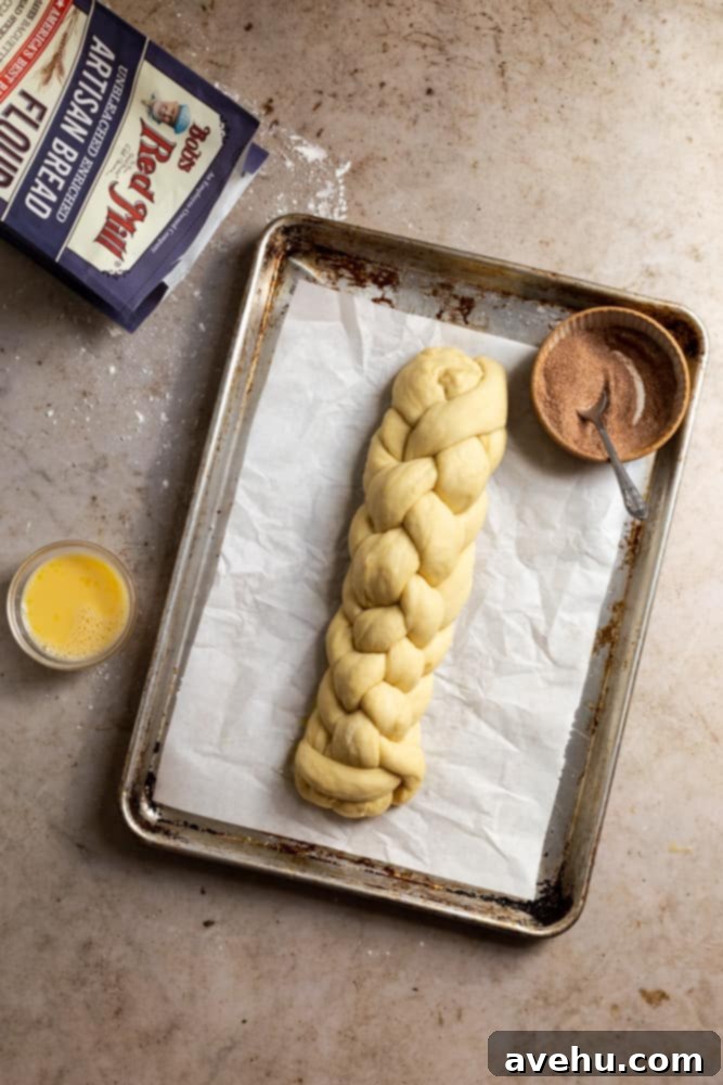 Homemade Challah Perfection 10 A perfectly formed 6-strand braided challah loaf resting on parchment paper on a sheet tray, ready for its second rise.