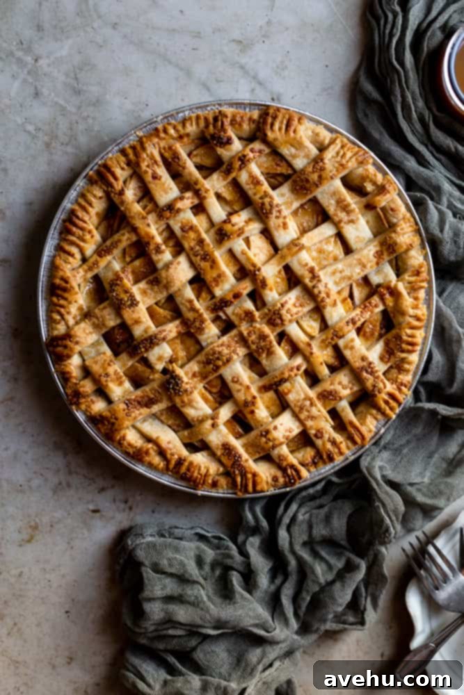 Sweet & Simple Caramel Apple Lattice Pie 2 A beautifully baked lattice-topped salted caramel apple pie cooling on a textured surface, ready to be sliced.