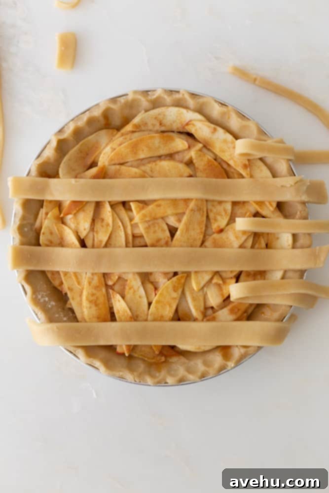 Sweet & Simple Caramel Apple Lattice Pie 10 Three alternating horizontal strips of pie crust peeled back to begin the weaving process for a lattice top.