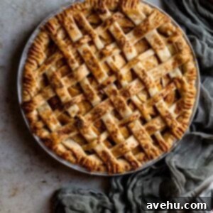 A lattice topped apple pie next to a green gauze napkin on a textured surface