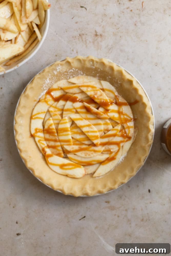 Sweet & Simple Caramel Apple Lattice Pie 6 The first layer of prepared apple slices and a drizzle of caramel sauce in an unbaked pie crust.