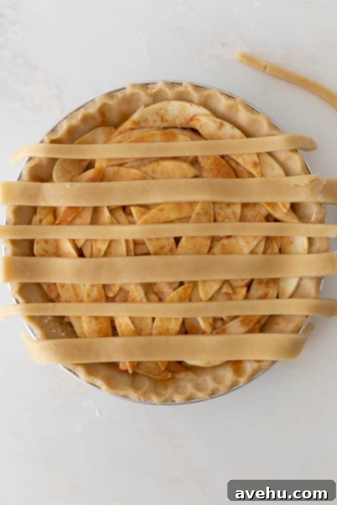 Sweet & Simple Caramel Apple Lattice Pie 9 An apple pie with six evenly spaced horizontal strips of pie crust laid over the filling.
