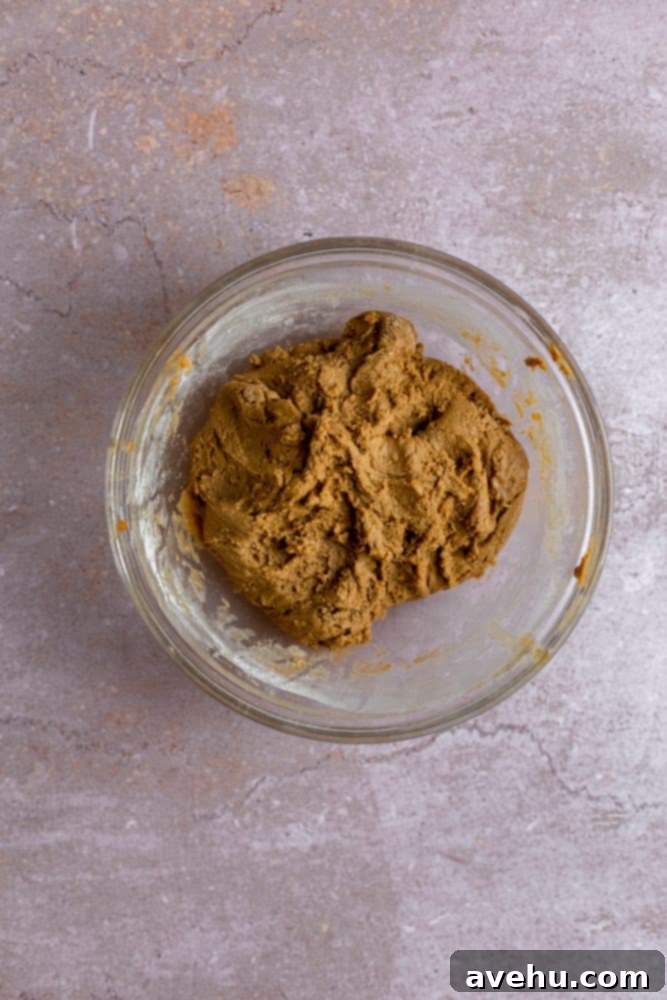 Gingerbread Biscotti with a Frosty Crunch 5 Finished batter for biscotti in a glass bowl on a pink background, ready for shaping.