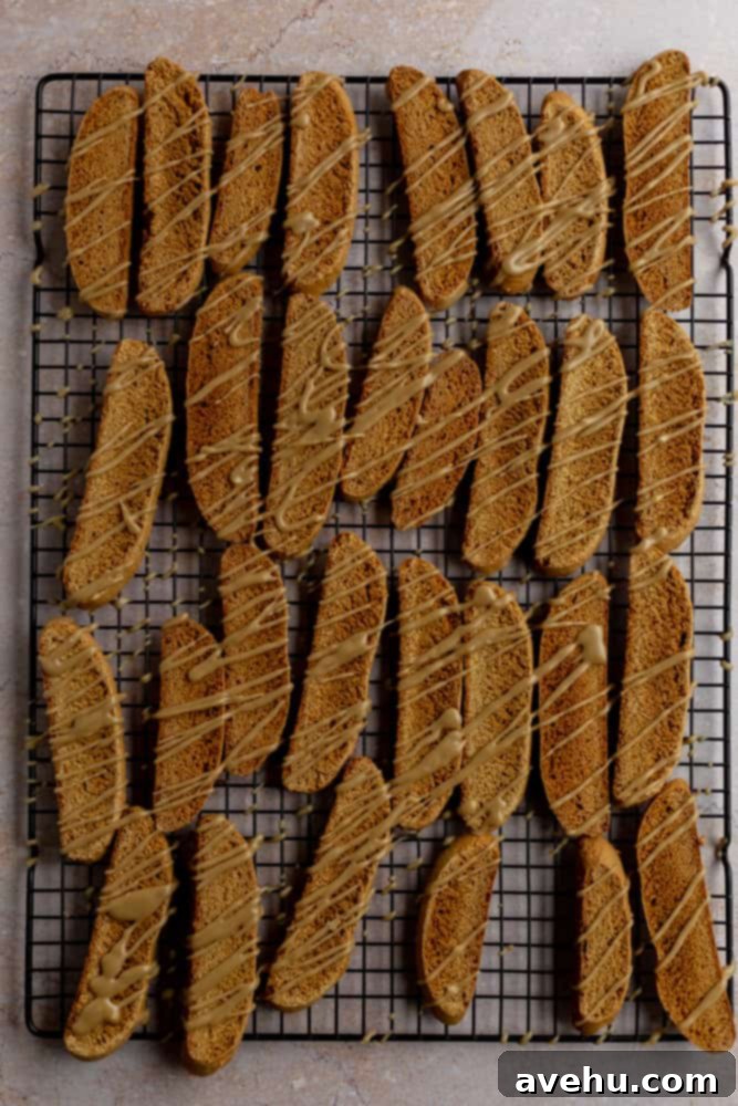 Gingerbread Biscotti with a Frosty Crunch 10 Glazed gingerbread biscotti cookies on a black cookie sheet, glistening with sweet brown sugar icing.