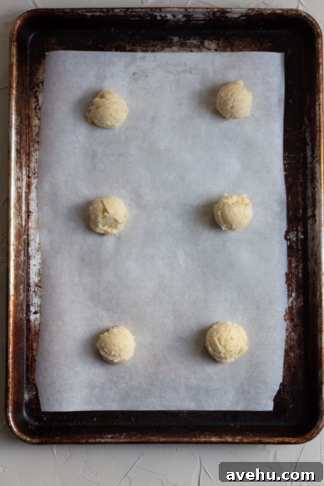 Cloud-Soft Italian Ricotta Cookies 6 Rows of perfectly portioned Italian ricotta cookie dough balls, neatly lined on a parchment-lined cookie sheet, ready for baking.