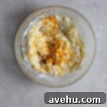 Cloudlike Cranberry Shortbread Delights 12 Cookie dough with orange zest in a glass bowl on a gray background, illustrating the precise step of adding aromatic zest.