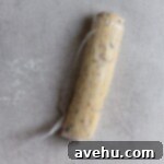 Cloudlike Cranberry Shortbread Delights 13 A log of cranberry orange shortbread dough tightly wrapped in plastic wrap, ready for chilling in the refrigerator.