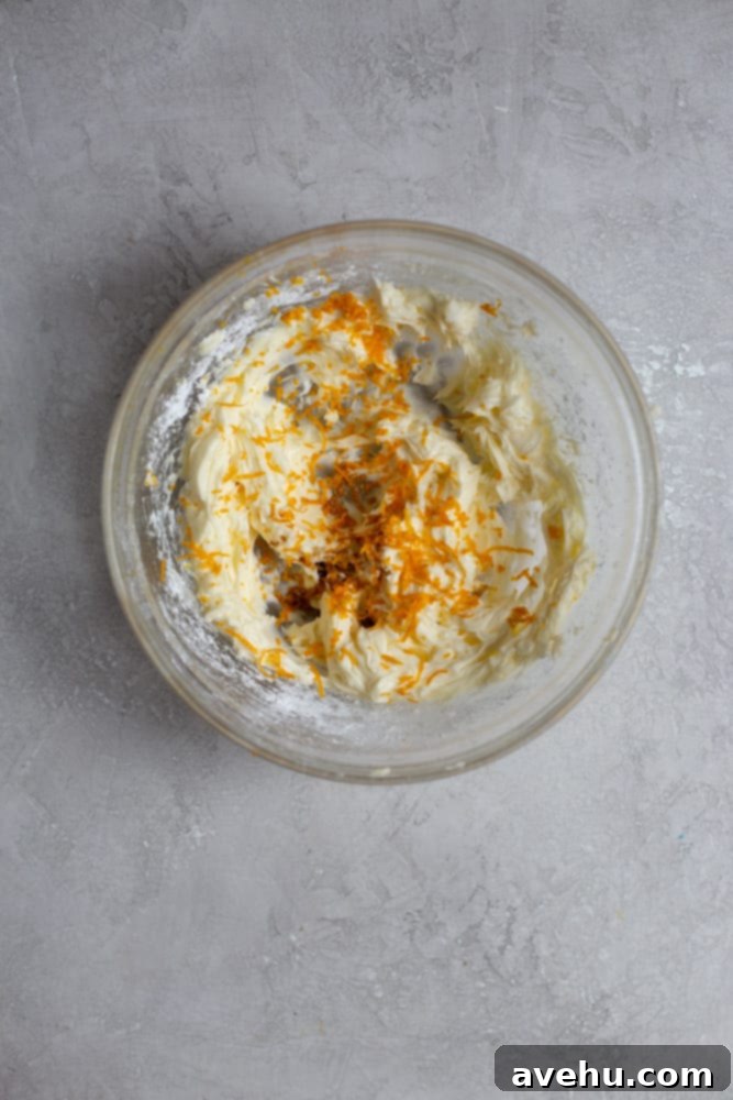 Cloudlike Cranberry Shortbread Delights 4 Mixing cookie dough with fresh orange zest in a glass bowl on a gray background, illustrating the precise step of adding aromatic zest.