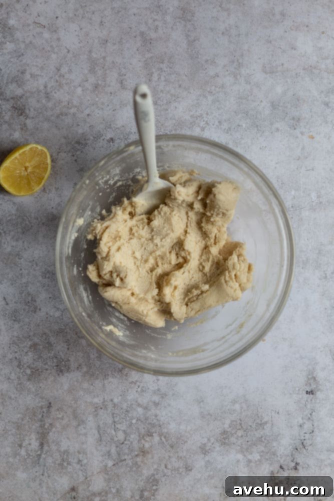 Cloud-Soft Lemon Shortbread 4 shortbread cookie batter in a glass bowl on a gray surface, showing the creamy texture before flour is added