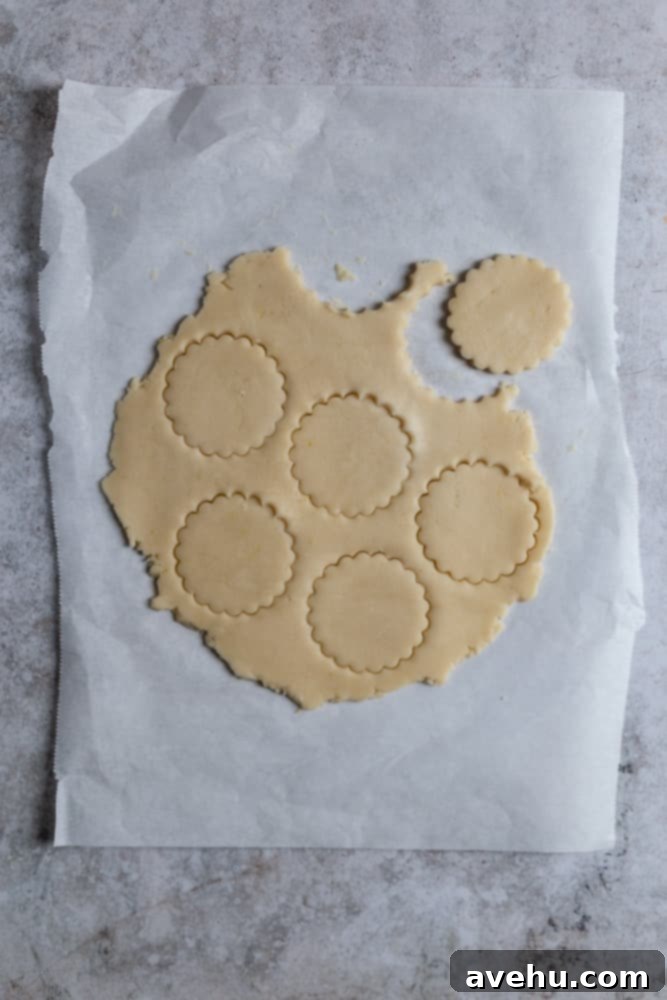Cloud-Soft Lemon Shortbread 7 Shortbread dough cut out into cookie shapes on a piece of parchment paper, ready for baking