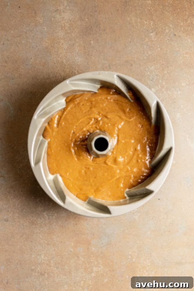 Foolproof Moist Carrot Bundt 7 Carrot Bundt Cake batter evenly poured into a prepared bundt pan, ready for baking.